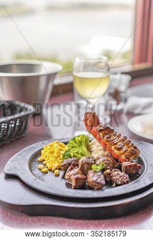 Beef Steack And Seafood Lobster Tail With Cheese, Corn And Broccoli On Plate With White Wine In Glas