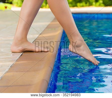 Woman Checking Water In The Swimming Pool.