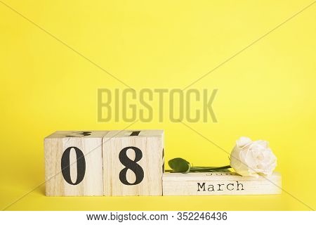Flat Lay сomposition March 8 Wooden Calendar With Flower On A Yellow Background With Space For Text.