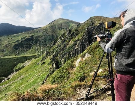 Back View Cameraman Shooting Mountain Landscape. Camera With Tripid, Film Making Process.