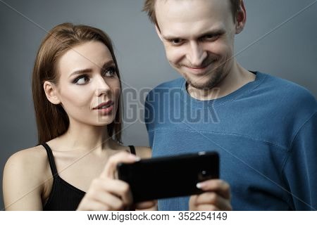 Cute Girl Shows Something Interesting To A Guy On A Smartphone They  Excitedly Looking At The Phone 