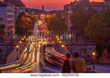 A Young Couple Is Sitting In Front Of A Beautiful Sunset Scenery In Germany, Munich
