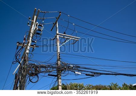 Electric Wires And Cables Installed On The Pole Looking Confused In Bangkok, Thailand With A Blue Sk