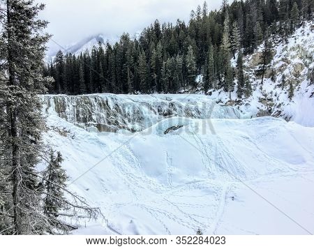 A Winter Setting Of A Frozen Waterfall Surrounded By Forests And Mountains At Wapta Falls, Yoho Nati