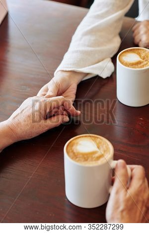 Close-up Image Of Young Woman Holding Hand Of Senior Mother And Telling Words Of Support When Thay A