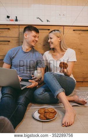 Lovely Caucasian Girl With Blonde Hair Is Eating Some Biscuits In The Kitchen On The Floor Near Her 