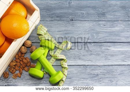 Lots Of Oranges, Dumbbells, Measuring Tape On A Wooden Textured Background. Fitness, Sports Nutritio