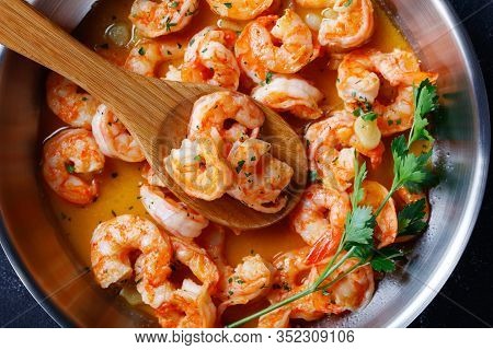 Italian Shrimp Scampi With Garlic Butter Sauce Served With Lemon And Parsley, On A Skillet On Concre