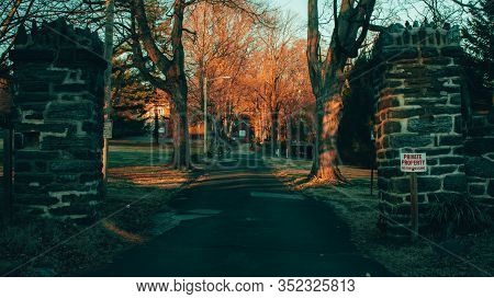 A Private Driveway With A No Trespassing Sign; Trees On The Sides Of The Driveway; And Cobble Stone 