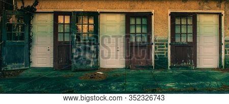 An Old Fashioned Three Door Garage With Big Red Doors And Broken Windows