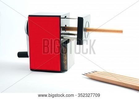 Rotary Pencil Sharpener. Red Black Rotary Pencil Sharpener With Brown Pencil On White Background.