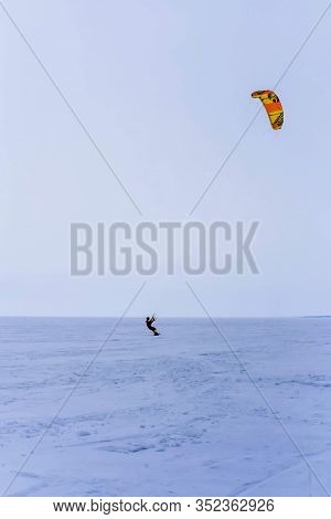 Kite Surfer Ride On Snowboard. Snowkiting In The Snow On Frozen Lake.