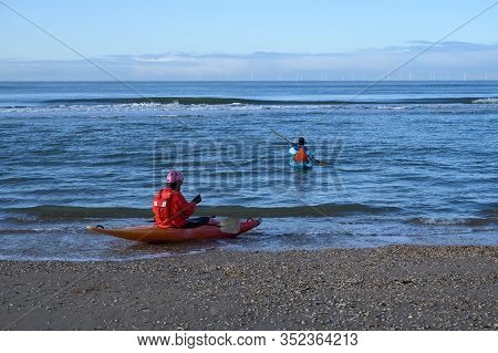 Unidentified People In Kayaks Going In To Water On North Sea Sandy Beach During Low Tide Near Castri