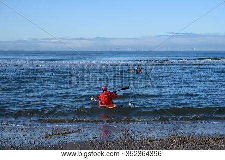 Unidentified People In Kayaks Going In To Water On North Sea Sandy Beach During Low Tide Near Castri