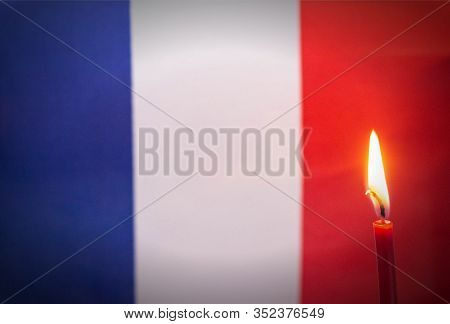 Burning Candle On The Background Of The Flag Of France. The Concept Of Mourning And Sorrow In The Co