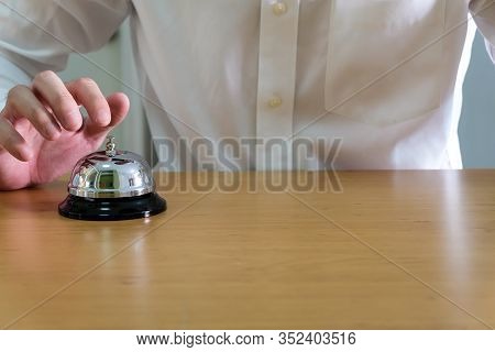 Men Wearing White Shirt Reaching His Hand And Finger To Ring A Reception Or Restuarant Bell On Wood 