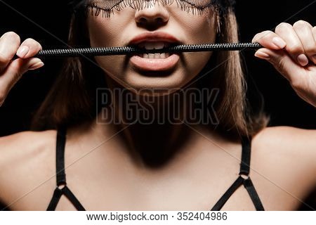 Cropped View Of Seductive Woman Holding Flogging Whip In Mouth Isolated On Black