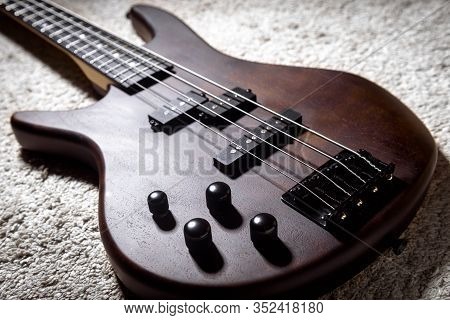 Left-handed Bass Guitar With Four Strings. Popular Rock Musical Instrument. Close View Of Brown Elec