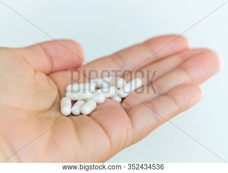 Medical Composition. A Handful Of Drugs In The Palm Of Hand. White Capsules On A Human Hand. Medical