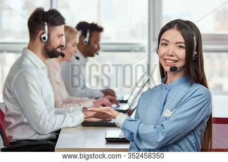 Young Female Operator Pointing Hand At Co-workers. Smiling Cheerful Asian Japaneese Girl Working In 