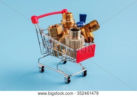 Red Shopping Cart With Plumbing Fittings Closeup. Brass Ball Valve, Y Filter, Tee And Polypropylene 