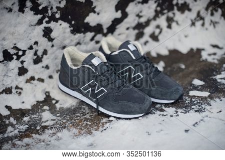 Dark Grey New Balance 574 Sneakers Shot Outdoor On Snowy Industrial Background. Krasnoyarsk, Russia 