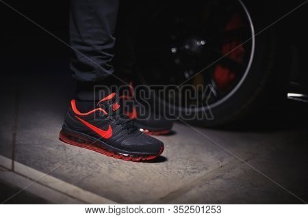 A Man Wearing Perfect Nike Air Max 2017 Sport Shoes Shot Near The Mercedez Benz Car On Dark Backgrou