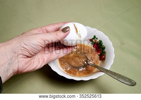 Raw Egg On A White Plate The Table, Small In It And A Spoon In A Womans Handon. Cooking Eggs For Coo