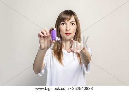 Young Woman Holds An Inhaler In Her Hand, Points Her Finger Right On A Light Background. Banner. Con