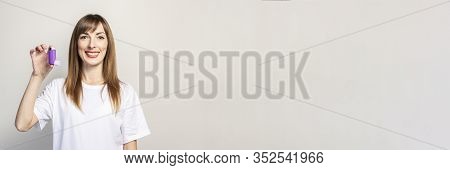 Happy Young Woman Holds An Inhaler In A Hand On A Light Background. Banner. Concept For Easier Breat