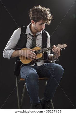Ung mand sidder og spiller en Ukelele