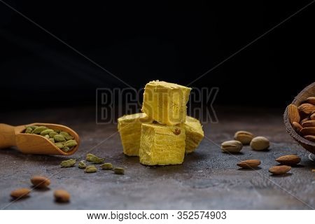 Cubed Pyramid Of Dessert Patisa, Cardamom Grains In Wooden Scoop, Pistachios And Almond On Concrete 