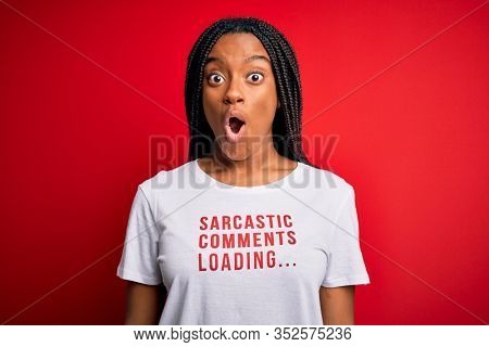 Young african american woman wearing sarcasm coments text on t-shirt over red background scared in shock with a surprise face, afraid and excited with fear expression