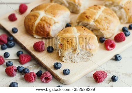 Traditional Hot Cross Buns Served With Bluberry And Raspberry On Wooden Cutting Board. Easter Pastry