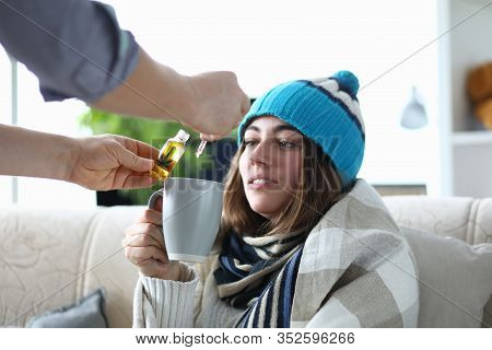 Portrait Of Tired Ill Lady Holding Cup Of Medication. Man Dripping Drops Of Medical Cannabinoid Oil 