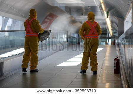 Otopeni, Romania - February 25, 2020: People Wearing Protective Suits Spray Disinfectant Chemicals O