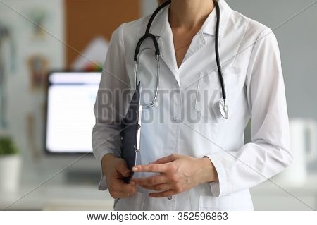 Close-up Of Experienced Doctor Working In Hospital. Practitioner Holding Paper Folder With Informati