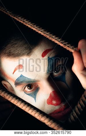 Close-up Portrait Of A Joker Man. Stock Photo Makeup Joker In A Horror Room.
