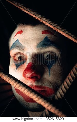 Close-up Portrait Of A Joker Man. Stock Photo Makeup Joker In A Horror Room.
