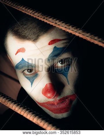Close-up Portrait Of A Joker Man. Stock Photo Makeup Joker In A Horror Room.
