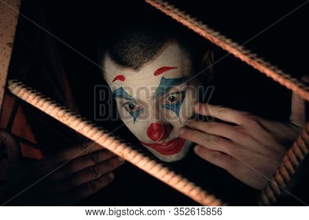 Close-up Portrait Of A Joker Man. Stock Photo Makeup Joker In A Horror Room.