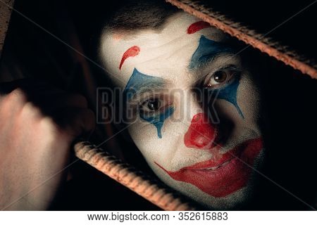 Close-up Portrait Of A Joker Man. Stock Photo Makeup Joker In A Horror Room.
