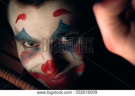 Close-up Portrait Of A Joker Man. Stock Photo Makeup Joker In A Horror Room.