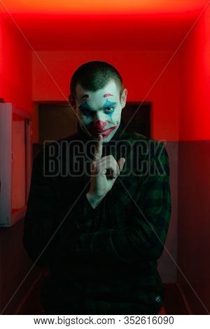 Close-up Portrait Of A Joker Man. Stock Photo Makeup Joker In A Horror Room.