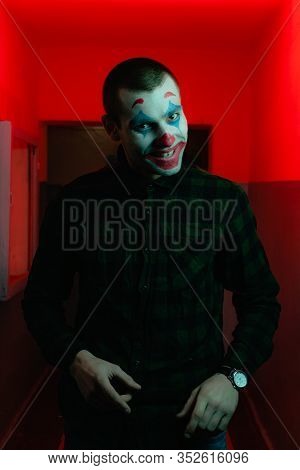Close-up Portrait Of A Joker Man. Stock Photo Makeup Joker In A Horror Room.