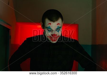 Close-up Portrait Of A Joker Man. Stock Photo Makeup Joker In A Horror Room.