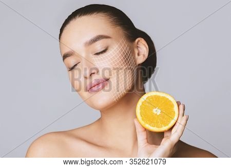 Vitamin C For Skin. Delighted Young Pretty Woman With Closed Eyes Holding Orange Half Over Grey Back