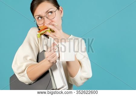 Girl Trying To Eat While Working. Blue Background