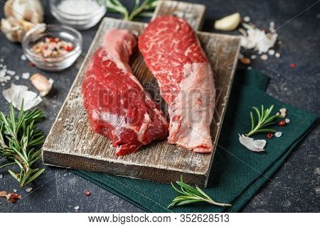 Raw Fresh Steak Sirloin Flap Served With Rosemary, Garlic And On Wooden Cutting Board. Black Angus B