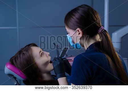 Close-up Portrait In The Dental Office. Doctor Dentist General Practitioner Examines A Patient Using